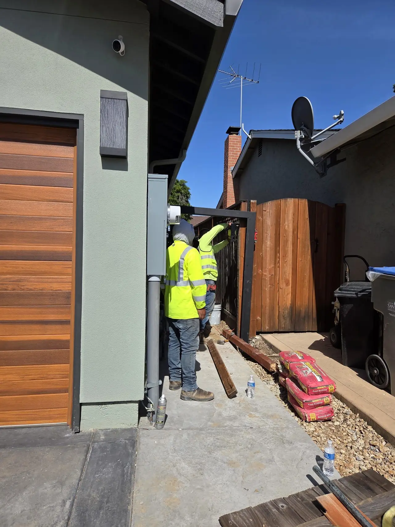 Two Eagle Fence & Gate installers mounting a steel gate frame beside a garage