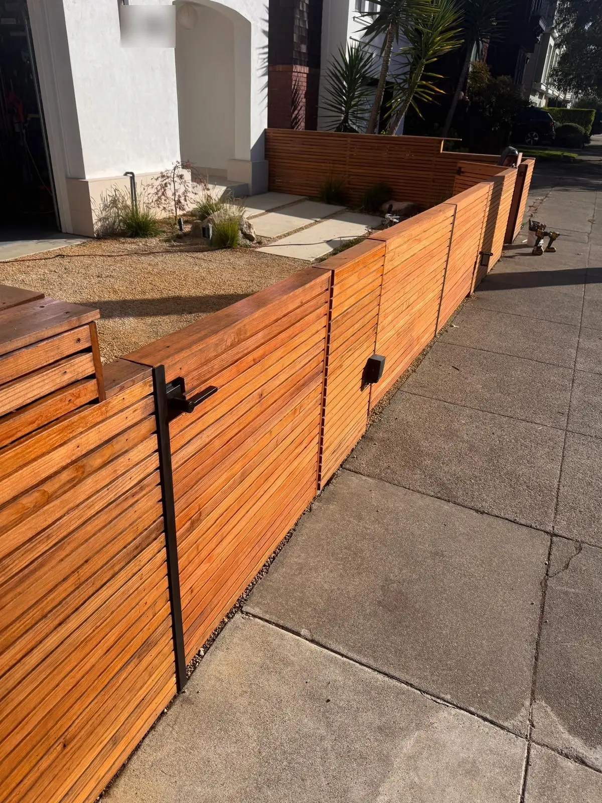 Modern horizontal redwood front-yard fence and gate along a city sidewalk
